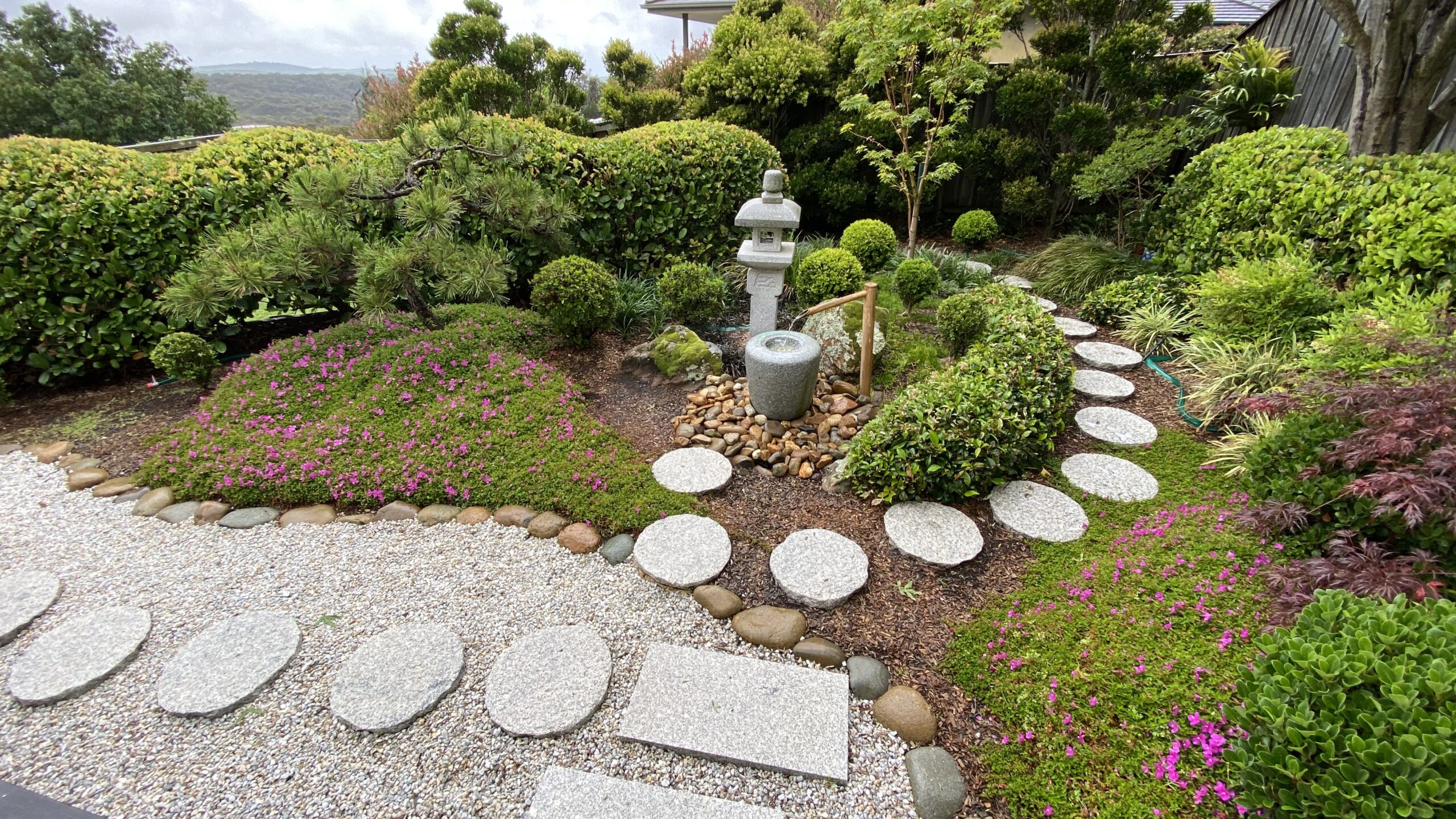 Well maintained Oriental garden with stepping stones, pruned and shaped greenery and a granite lantern